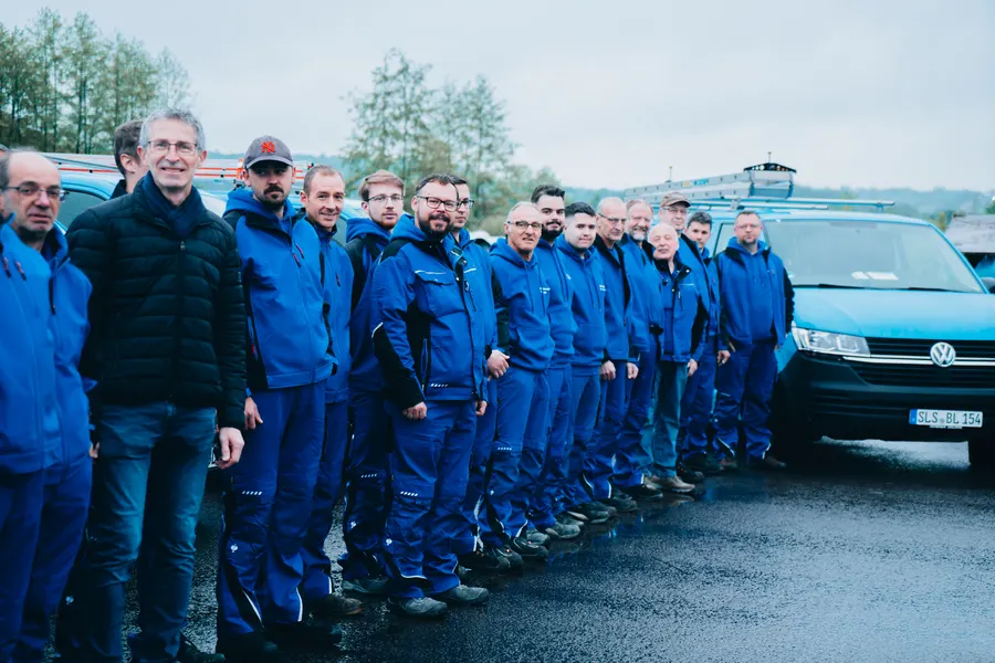 Professionelle Betriebsfotografie: komplettes Team mit Fahrzeugflotte vor dem Betrieb